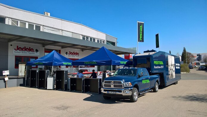 3x3m blue event gazebo customised with green Festool logo combined with company van and caravan in front of DIY shop Jedele