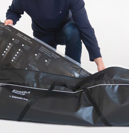 The man packs the folding gazebo side walls in the black side wall bag.