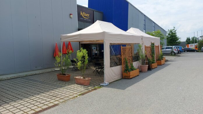 2 folding gazebo measuring 4.5x3 m stand in front of the Käser bakery in Vilshofen. They serve as canopies for the guests.